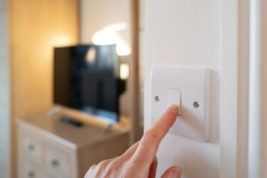 Person turning off a switch in a lit-up room