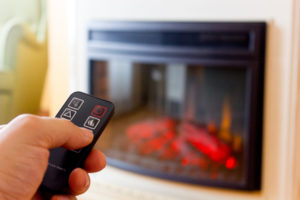 Person with remote adjusting electric fireplace